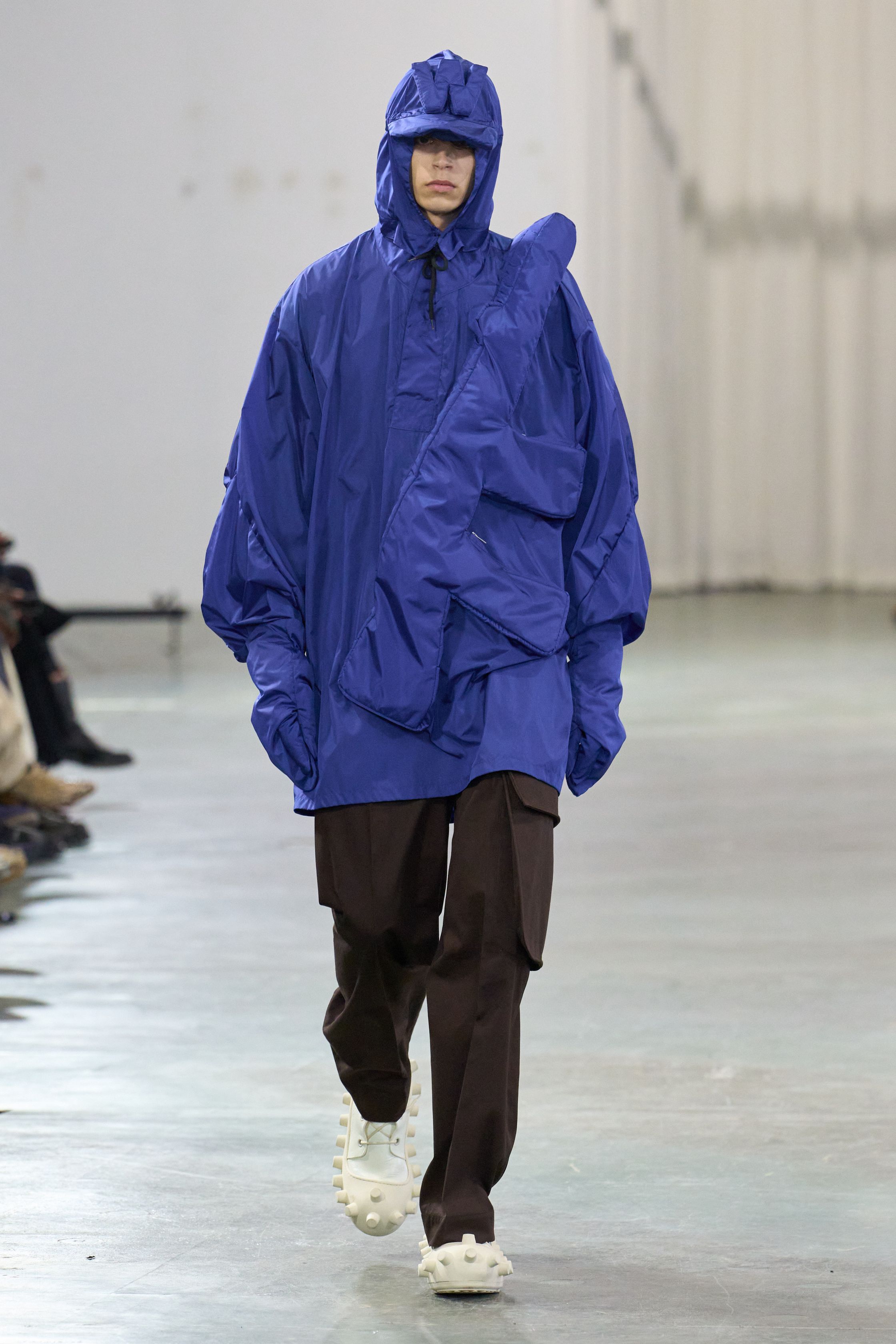 Walter Van Beirendonck 2026秋冬以高度饱和的色彩、夸张比例与童真符号继续挑战男性气质的既定边界。针织花朵、卡通图案、结构化西装与机能裤装并置，构建出介于游戏、政治隐喻与乌托邦幻想之间的舞台。系列拒绝低调，刻意制造视觉噪音，用快乐、怪诞与不合时宜的色彩作为对现实焦虑的反击，呈现一场毫不妥协的时装宣言-顽石频道趋势研究